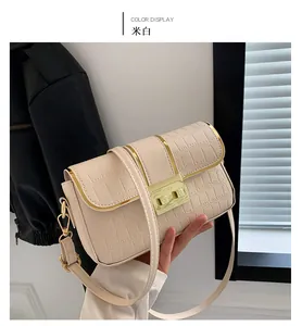 Close-up of cream crossbody bag with crocodile embossing and gold buckle hardware