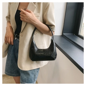 Borsa hobo nera con trama a coccodrillo indossata da una modella in stile urbano