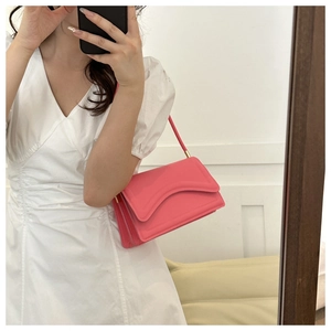 Pink underarm shoulder bag featuring a unique wavy flap design and gold hardware detail