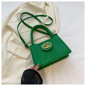 Close-up of bright green handbag with radial embossed pattern and gold heart lock