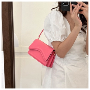 Close-up detail of candy red underarm bag with unique curved flap and layered structure