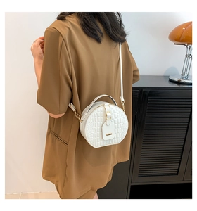 Detailed back view of white round crossbody bag with crocodile texture and gold hardware