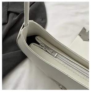 Detailed close-up of the smooth silver metal zipper and white leather finish on a bag