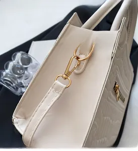 Close-up of golden hardware and wavy embossed texture on cream leather handbag