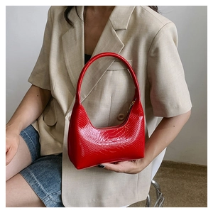 Dettaglio borsa rossa con trama a coccodrillo, zip dorata e finitura lucida chic