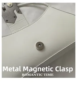 Detailed macro view of white leather bag featuring a magnetic metal buckle closure