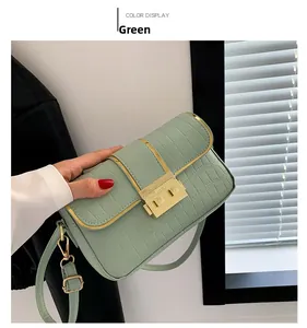 Close-up of green crocodile pattern handbag with gold metal clasp and buckle detail