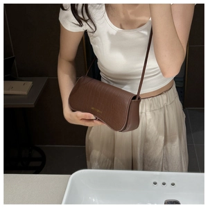 Détail du sac sous le bras marron avec motif crocodile et logo doré élégant
