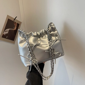 Silver metallic bucket bag with pleated design and bow accents on silver chain strap