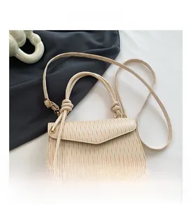 Detail view of the beige pleated handbag texture with shoulder strap and flap closure