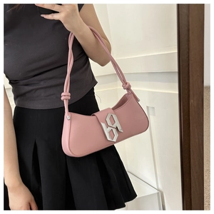 Detail of pink underarm bag featuring silver hollow metal logo and knotted shoulder strap
