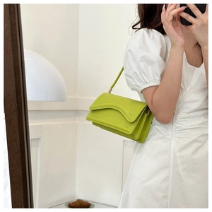 Neon green shoulder bag with unique wavy flap shown in a mirror selfie style