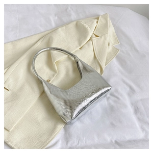 Vista macro della borsa a mezzaluna argento con trama a serpente su blazer beige