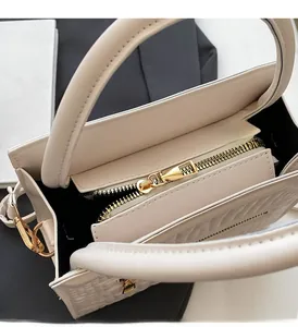 Close-up of smooth golden zipper and quilted interior detail on cream crossbody bag