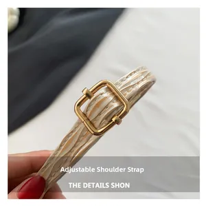 Macro shot of an adjustable shoulder strap with cream texture and a gold metal buckle