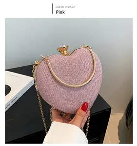 Detail of pink heart-shaped clutch bag with glitter texture and gold metal snake handle
