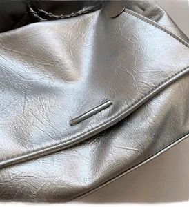 Détail du sac en similicuir argenté métallisé avec bandoulière chaîne et garniture