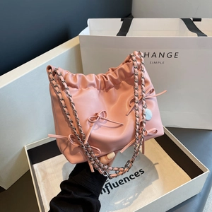 Pink pleated bucket bag with bow accents and silver chain strap shown in a gift box