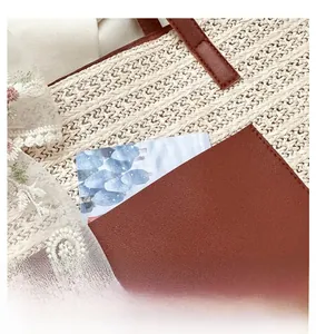 Detail of woven straw tote bag with brown leather pocket and romantic art card insert