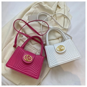Close-up of quilted handbag with golden V-heart buckle in fuchsia and white colors