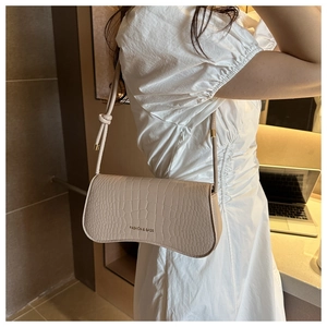 Détail de la texture croco beige et du nœud décoratif sur un sac à bandoulière croissant