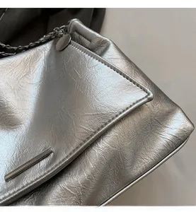 Détail d'un sac cabas argenté métallisé avec texture plissée et bandoulière en chaîne