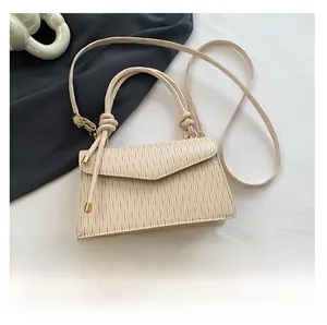 Detail of cream pleated crossbody bag showing triangle flap and knot handle details
