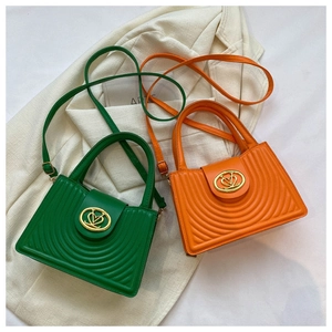 Detail of green and orange quilted handbags with heart-shaped gold buckles on a blazer
