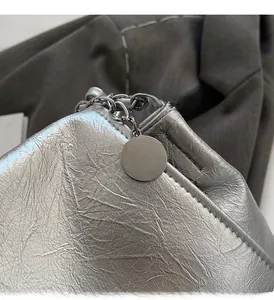 Détail de la texture en cuir argenté métallisé et du pendentif rond poli du sac à main
