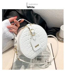 Detailed close-up of white round crossbody bag with faux crocodile texture and gold hardware