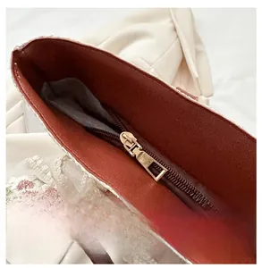 Detail of a smooth golden metal zipper with dark brown lining and white lace embroidery