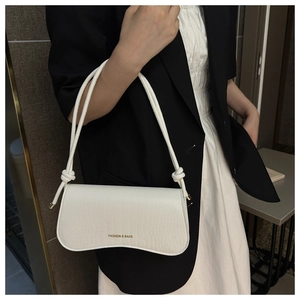 Détail du sac sous l'aisselle blanc à motif crocodile avec lanière nouée et texte doré