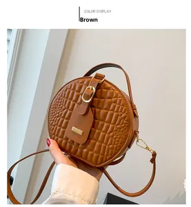 Close-up of brown crocodile embossed round handbag with elegant gold hardware and top handle