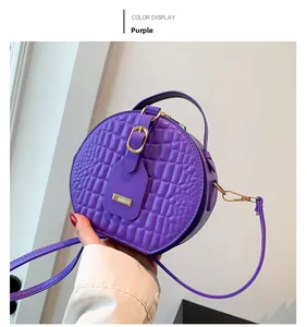 Close-up of purple crocodile pattern round handbag with golden hardware details