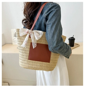 Détail du sac cabas en paille avec poche en cuir marron et nœud en dentelle florale