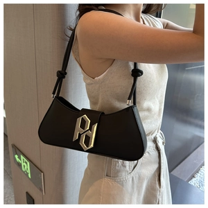 Side view of black leather baguette bag with golden PD logo on a female model