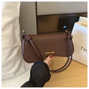 Détail du sac à bandoulière marron motif crocodile avec lettrage doré et nœud décoratif
