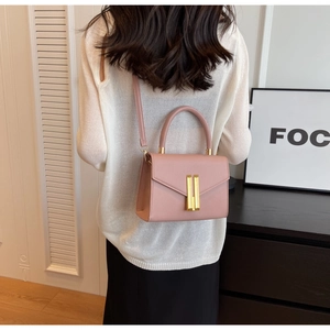 Detail of trendy pink crossbody bag with elegant gold metal clasp and leather strap