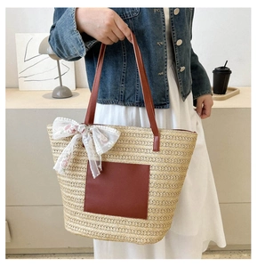 Détail du sac en paille avec bandoulières en cuir marron et nœud en dentelle florale