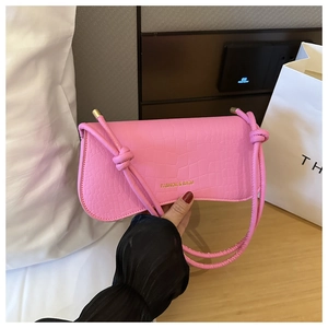 Détail du sac sous le bras rose à motif croco avec bandoulière nouée et métal doré