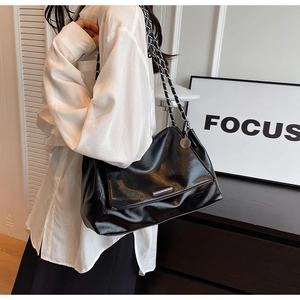 Détail du sac bandoulière plissé noir avec chaîne argentée et ornements métalliques