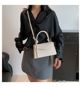 Detail of cream-colored pleated handbag with knot handle and elegant texture