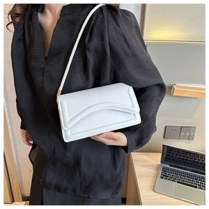 Detail of light grey flap bag showing curved stitching layered design and thin strap