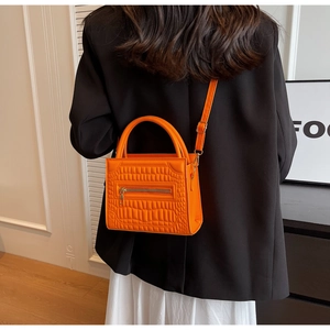 Detailed back view of orange crocodile pattern PU leather handbag on model with round handle