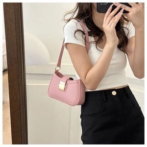 Détail du sac sous les aisselles rose avec boucle en métal doré sur un t-shirt blanc