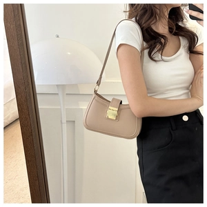 Sac porté épaule beige avec fermoir rectangulaire doré porté par un mannequin