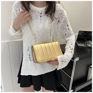 Crossbody view of a gold glossy quilted chain bag with elegant embroidery and metal strap