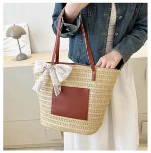 Gros plan du sac cabas en paille avec poche en cuir marron et nœud en dentelle blanche