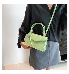 Detail of light green pleated crossbody bag with knot decor and magnetic closure