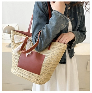 Détail d'un grand sac cabas en paille avec des anses en cuir et un nœud floral en dentelle